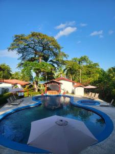 a swimming pool with an umbrella in the middle at Agua Dulce Beach Resort in Puerto Jiménez