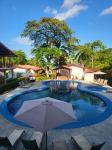 a pool at a resort with an umbrella at Agua Dulce Beach Resort in Puerto Jiménez