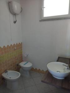 y baño con aseo, bidet y lavamanos. en Borgo del Tennis - Sa Ventana 2, en Badesi