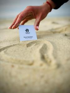 a person reaching for a piece of paper in the sand at Apartament White glove Nowe Zatorze in Olsztyn