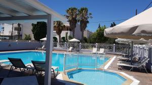 a swimming pool with chairs and umbrellas on a building at Dinos Pool Apartment in Kardamaina