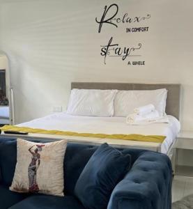 Cama en habitación con sofá y pared en Jomana Luxury Apartments, en Lusaka