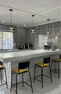 una cocina con un gran mostrador blanco con 4 taburetes en Jomana Luxury Apartments, en Lusaka