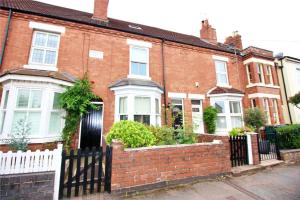 a red brick house with a white fence at Exceptionally Stunning Four Bed Terraced House With Two Bathrooms- Recently Renovated in Spon End