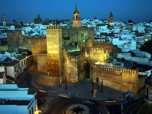 a building with a clock tower in a city at night at Apartamento Karmo in Carmona +8 photos