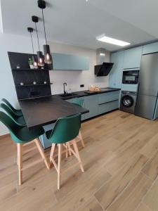 a kitchen with a black table and green chairs at ÁTICO TERESA BORA PALM, PISCINA PRIVADA CLIMATIZABLE 250m playa in Vera