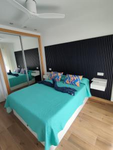 a bedroom with a blue bed with a large mirror at ÁTICO TERESA BORA PALM, PISCINA PRIVADA CLIMATIZABLE 250m playa in Vera +37 photos