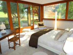 Schlafzimmer mit einem Bett, einem Schreibtisch und Fenstern in der Unterkunft Villa with Lake Geneva views; 1960 (mid century modern) style in Neuvecelle