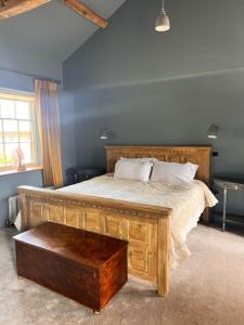 um quarto com uma cama com uma estrutura em madeira e uma mesa em Apartment at Llanerchydol Hall em Welshpool