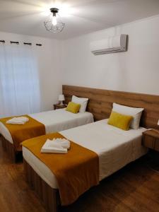 two beds in a hotel room with towels on them at A Casa da Formosinha in Madalena