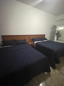 Dos camas en un dormitorio con sábanas azules. en Hotel Costa Linda Beach Boca Chica, en Boca Chica