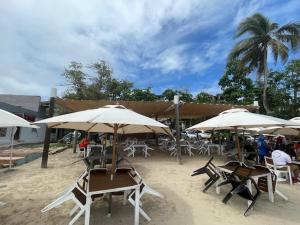 a group of tables and chairs with umbrellas on a beach at Hotel Costa Linda Beach Boca Chica in Boca Chica