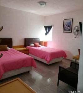 Duas camas num quarto com lençóis cor-de-rosa e uma janela. em Club Campestre El Eden em Yautepec