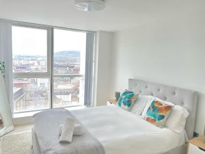 a bedroom with a white bed with large windows at 22nd Floor Luxury City Centre Apartment in Belfast