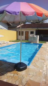 an umbrella sitting next to a swimming pool at Casa com Piscina na Morada da Praia in Bertioga