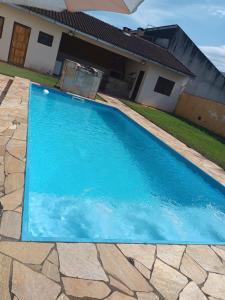 a blue swimming pool in front of a house at Casa com Piscina na Morada da Praia in Bertioga