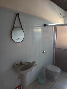 a bathroom with a sink and a toilet and a mirror at Casa com Piscina na Morada da Praia in Bertioga