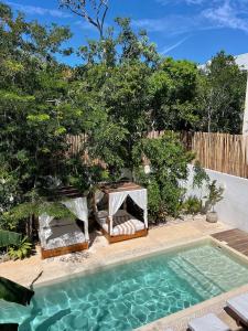 una piscina con 2 sillas y un cenador en Villa Sorella in Aldea Zama 24Hrs Security, 5min to the beach en Tulum