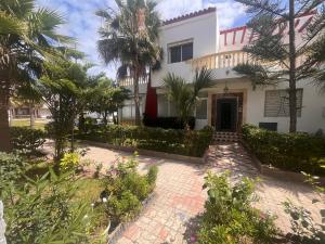 Casa blanca con palmeras y patio en Golden Beach Villa Casablanca, en Sidi Rahal