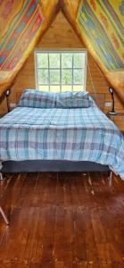 uma cama num quarto de madeira com uma janela em Cabaña el rincon de la abuela em Guasca