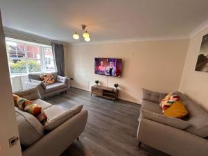 a living room with two couches and a tv at Vyna Place-Close to City Hospital in Nottingham