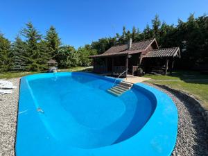 a large blue swimming pool in front of a house at Łęgowska Dolina in Olecko