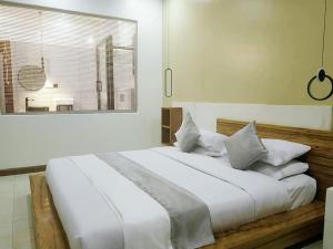 una camera da letto con un grande letto con lenzuola e cuscini bianchi di Isabirye residence a Kampala