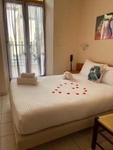 ein Schlafzimmer mit einem großen weißen Bett mit roten Rosen darauf in der Unterkunft Hôtel Elaïa in Corps