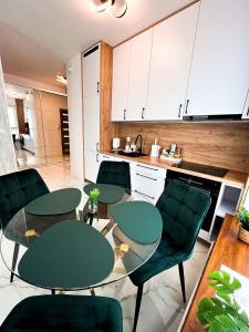kuchnia z dwoma stołami i zielonymi krzesłami w obiekcie Apartament Chełm w mieście Chełm