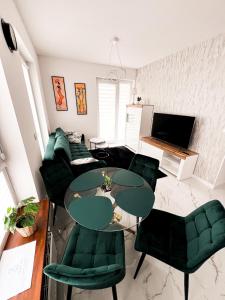 sala de estar con sillas verdes y mesa de cristal en Apartament Chełm, en Chełm