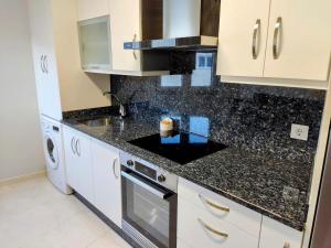 a kitchen with white cabinets and a black counter top at Apartamento en Fisterra con vistas al mar, 3º sin ascensor in Fisterra +4 photos