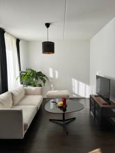 Tranquil and Convenience Southern Malmo Apartment في مالمو: غرفة معيشة مع أريكة بيضاء وطاولة