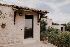 un pequeño edificio de piedra con una puerta grande en Agriturismo Balcone Mediterraneo - Camere, en Ragusa