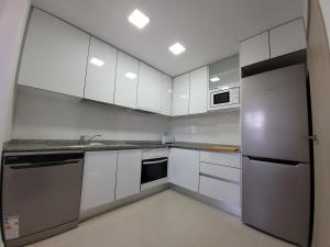 a kitchen with white cabinets and a stainless steel refrigerator at Chalet adosado acogedor Busot in Alicante