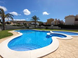 a swimming pool in a yard with palm trees and houses at Chalet adosado acogedor Busot in Alicante