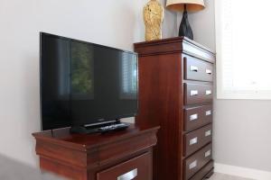 a flat screen tv on a wooden stand with a dresser at LOCATION LOCATION LOCATION IMMACULATE 1 BEDROOM SUITE in Victoria
