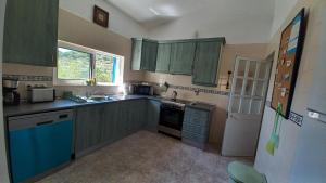 una pequeña cocina con armarios verdes y fregadero en Casa dos Amigos - NEW management, en Estói