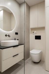 a bathroom with a sink and a toilet and a mirror at Mazuria Apartament nad jeziorem Drwęckim in Ostróda
