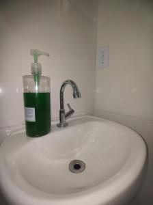 un vaso de líquido verde sentado en un fregadero en Apartamento Studio PNG novo e confortável en Paranaguá