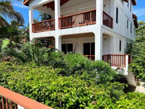 a white building with a balcony and some bushes at VeLento Partial Ocean View #6 in Caye Caulker