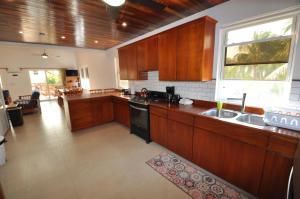 cocina con armarios de madera, fregadero y ventana en VeLento Partial Ocean View Penthouse #7, en Caye Caulker
