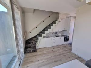 a kitchen with white cabinets and a staircase at Pajūrio Ąžuolo Istorija 9 in Palanga
