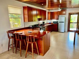 uma cozinha com armários de madeira e uma ilha com bancos de bar em VeLento Oceanfront Penthouse #3 em Caye Caulker