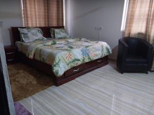 a bedroom with a bed and a chair at EuChris Homes in Kumasi