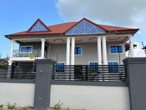 ein Haus mit rotem Dach auf einem Zaun in der Unterkunft EuChris Homes in Kumasi