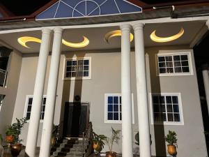a large white house with white columns and yellow lights at EuChris Homes in Kumasi
