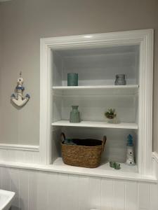 a white shelf in a bathroom with a basket on it at Class Apartments in Peterhead