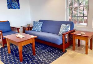 a living room with a blue couch and two tables at VeLento Oceanfront #4 in Caye Caulker