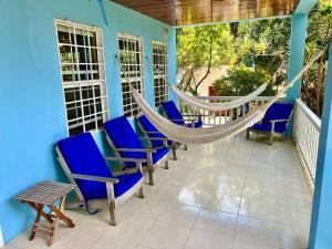 een veranda met blauwe stoelen en een hangmat bij Sandy's Secret in Caye Caulker