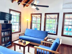 Una sala de estar con un sofá azul y un televisor. en Barbara's Beach House, en Caye Caulker